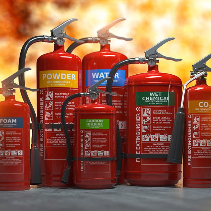 Fire extinguishers on a fire background. Various types and different sizes of extinguishers.